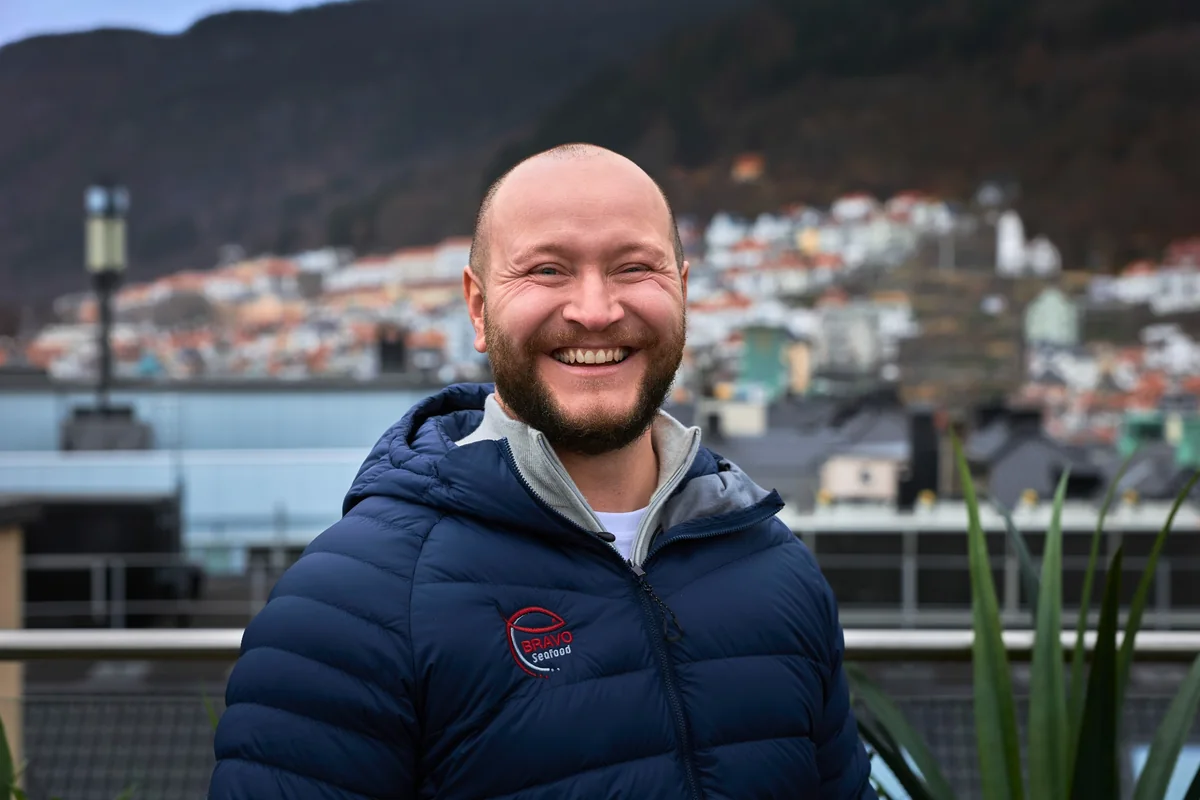 Smilende medarbeider hos Bravo Seafood med Bergen i bakgrunnen
