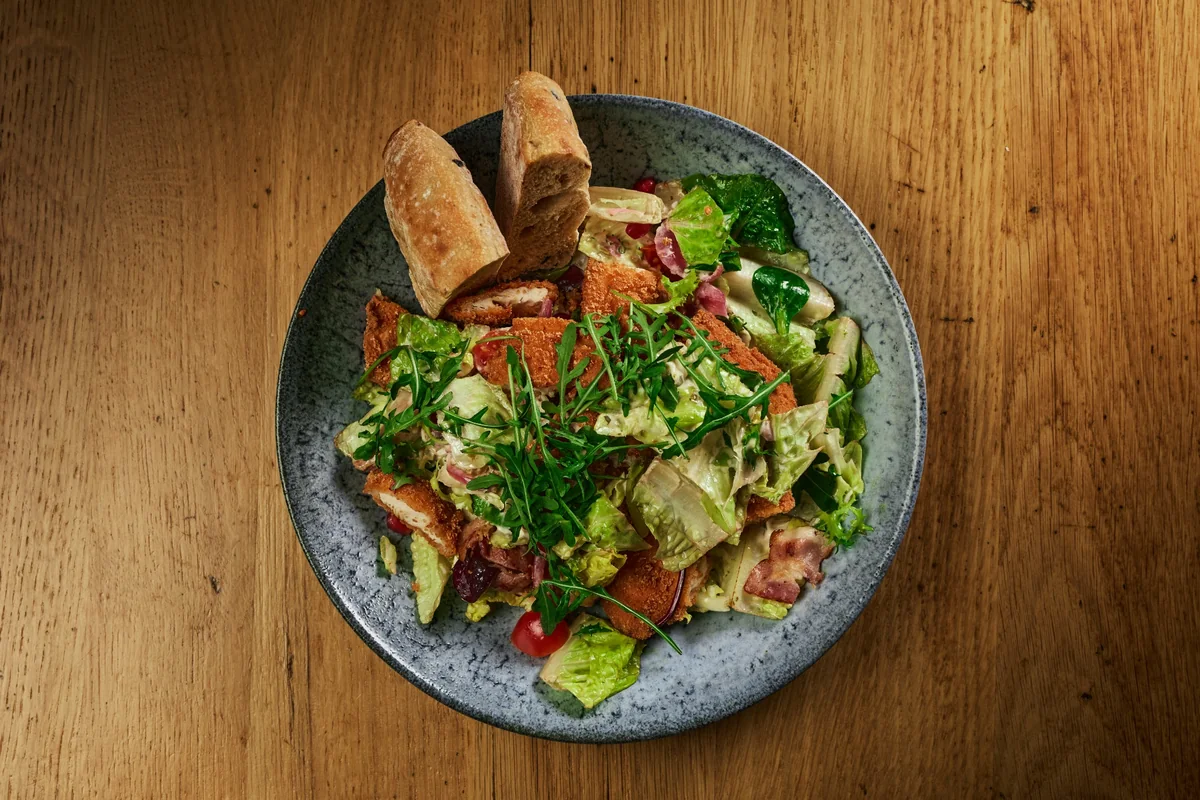 Salat med kylling og brød fotografert ovenfra på et trebord